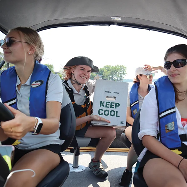 Four LakeSmart team members in their boat with a box of seedlings