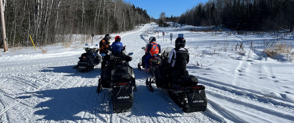 Snowmobilers take a break beside the trail.